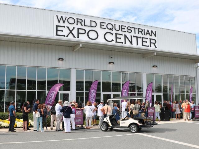 The World Equestrian Center Expo Center facade with purple feather flags advertising the Ocala Food and Wine Festival. Attendees await entry.