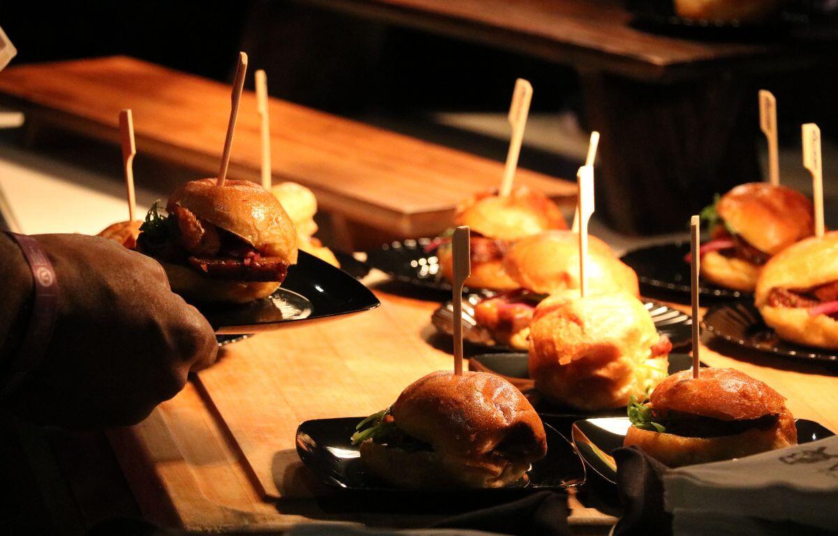 Multiple sliders are lined up on a wooden table with wooden stick poking out from the top of them.