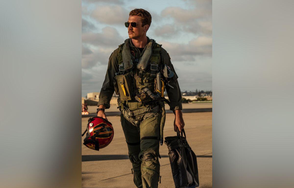 Actor in flight gear walking on runway, promotional still from Top Gun: Maverick.