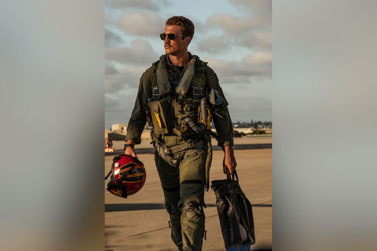 Actor in flight gear walking on runway, promotional still from Top Gun: Maverick.
