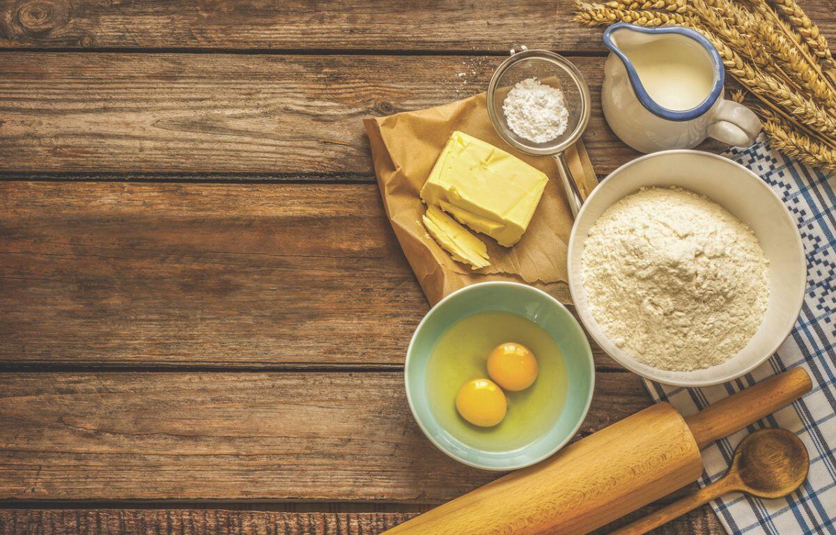 Food ingredients and cooking utensils resting on a wooden surface.