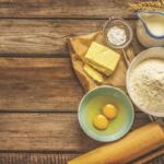 Food ingredients and cooking utensils resting on a wooden surface.