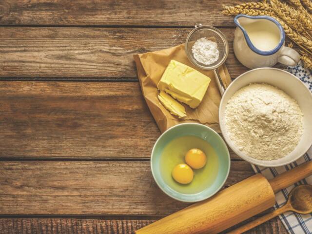 Food ingredients and cooking utensils resting on a wooden surface.