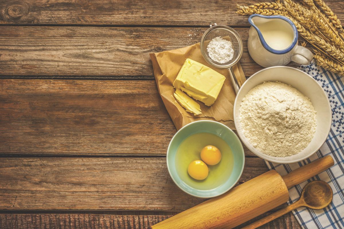 Food ingredients and cooking utensils resting on a wooden surface.