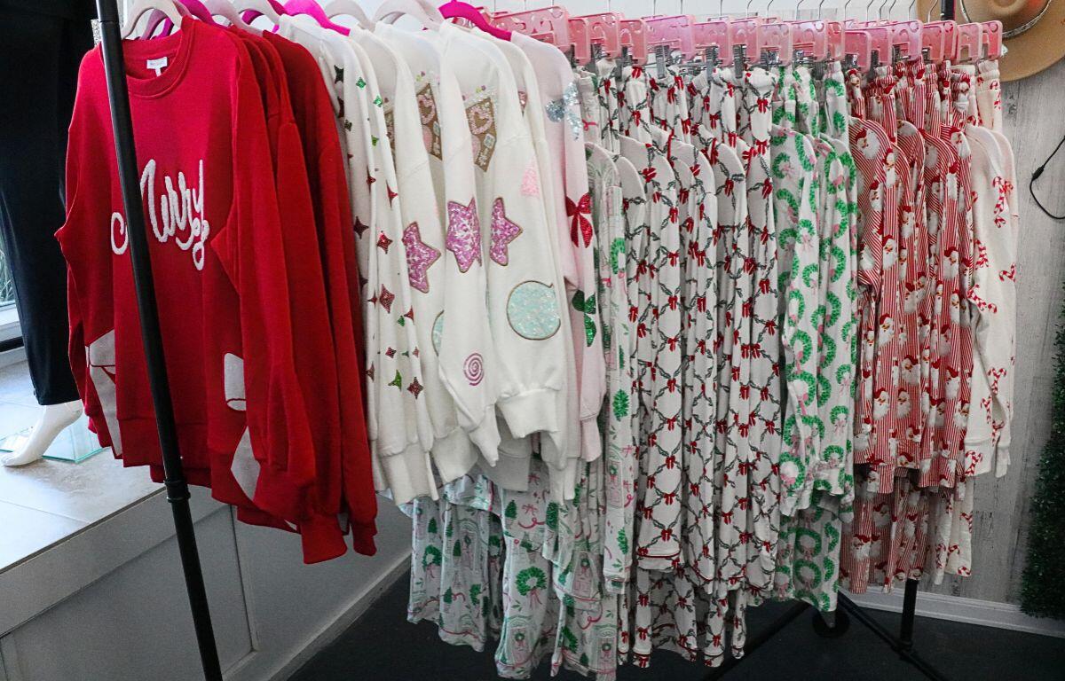 A rolling rack full of festive holiday pajamas in various colors sat near a store window.
