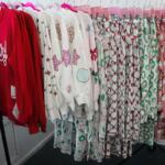 A rolling rack full of festive holiday pajamas in various colors sat near a store window.