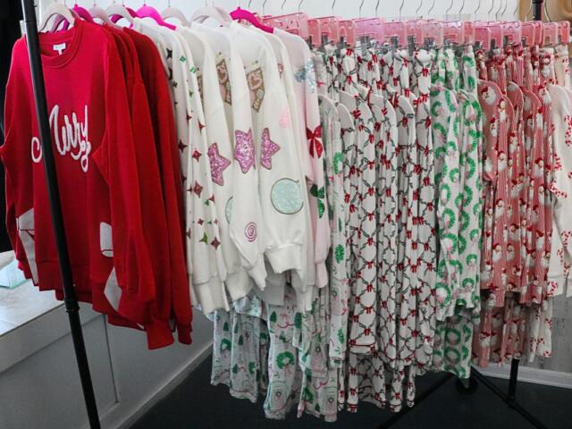 A rolling rack full of festive holiday pajamas in various colors sat near a store window.