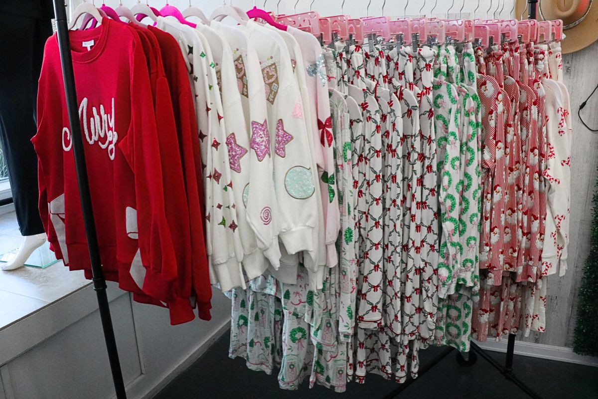 A rolling rack full of festive holiday pajamas in various colors sat near a store window.