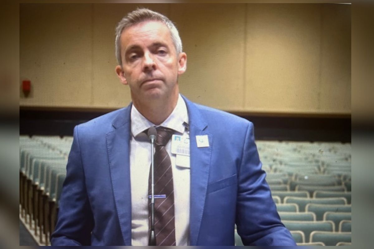 A well-dressed man standing in front of rows of empty seats.