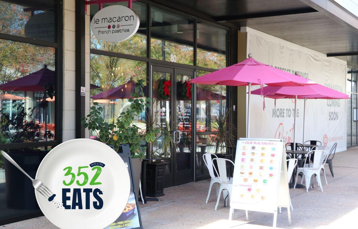 Outdoor seating at Le Macaron French Pastries in Gainesville, with pink umbrellas and a 352 Eats sign near the entrance.