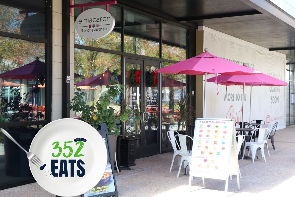 Outdoor seating at Le Macaron French Pastries in Gainesville, with pink umbrellas and a 352 Eats sign near the entrance.