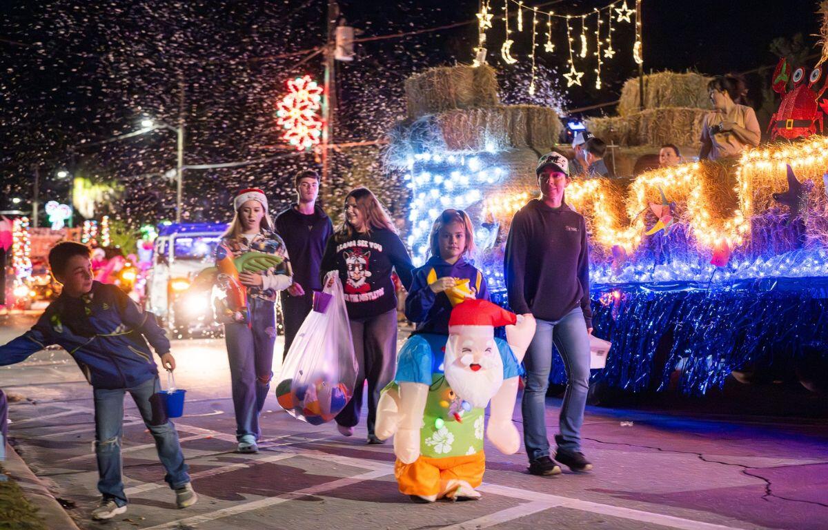 A group of people walking besides a decorated trailer with haybale designs.