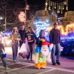 A group of people walking besides a decorated trailer with haybale designs.
