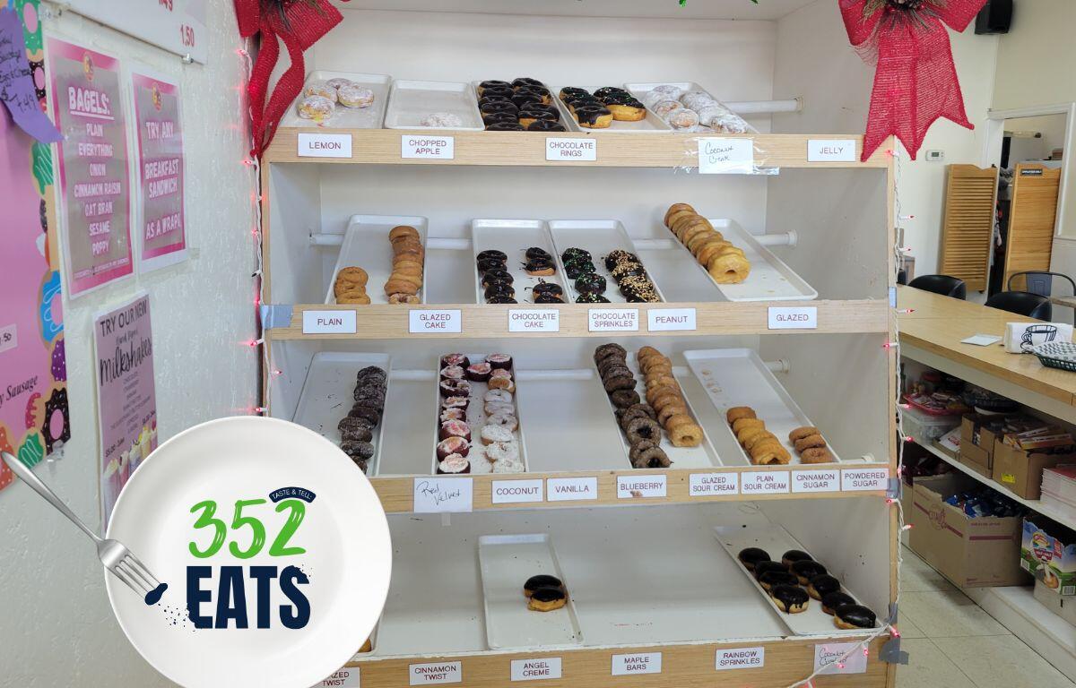 A display case filled with assorted donuts, showing multiple flavors arranged on shelves.