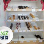 A display case filled with assorted donuts, showing multiple flavors arranged on shelves.