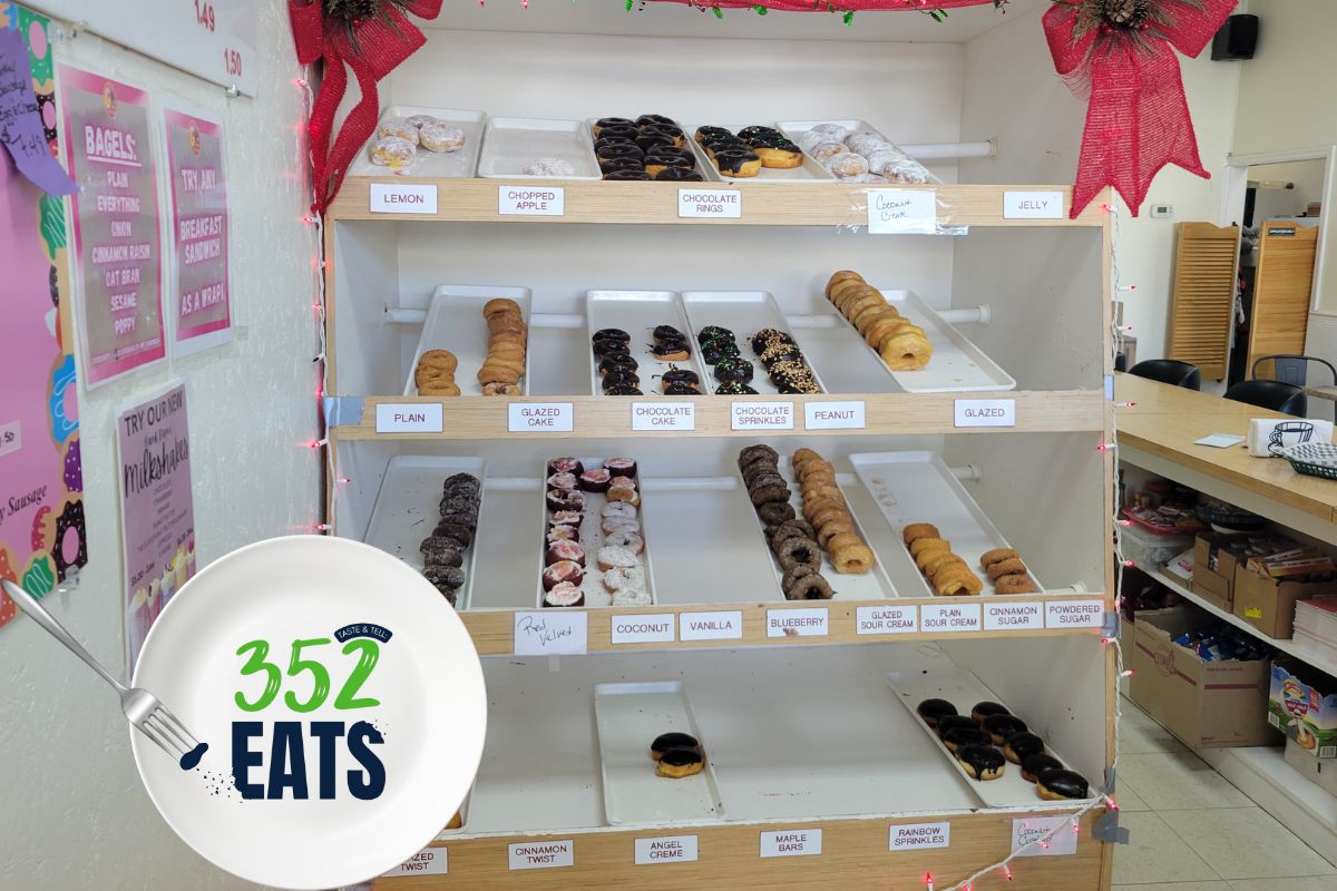 A display case filled with assorted donuts, showing multiple flavors arranged on shelves.