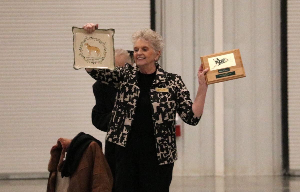 A woman stands with two awards in hand in a large expo center.