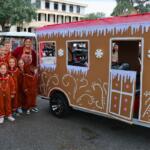 A group of kids pose for a picture next to a golf cart decorated to look like a gingerbread house.