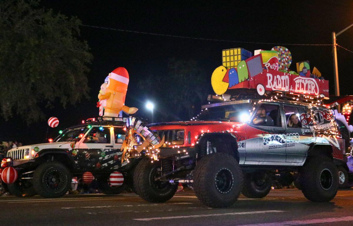 Cars with advertisements on the side feature inflatables and toy-themed decorations on top as well as Christmas lights and candy caned themed decorations.