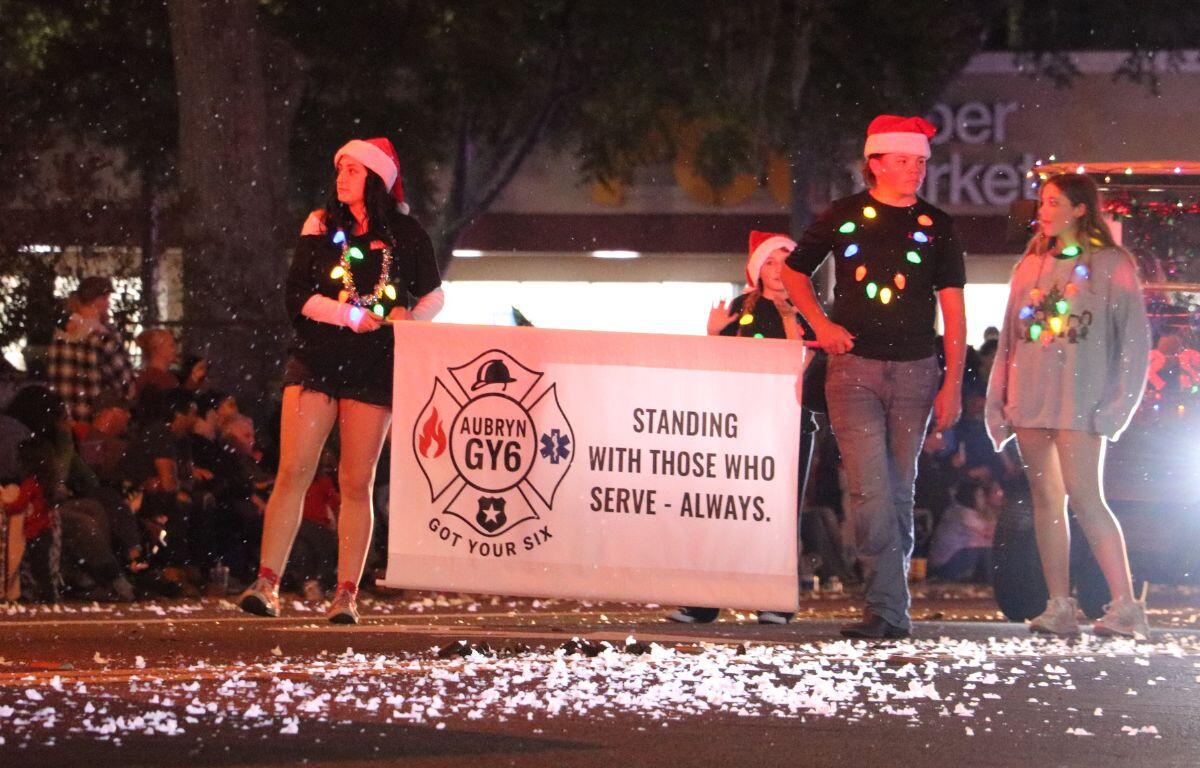 Two people walk on a road holding a white sign reading, "Aubryn GY6." The sign shows support for first responders.
