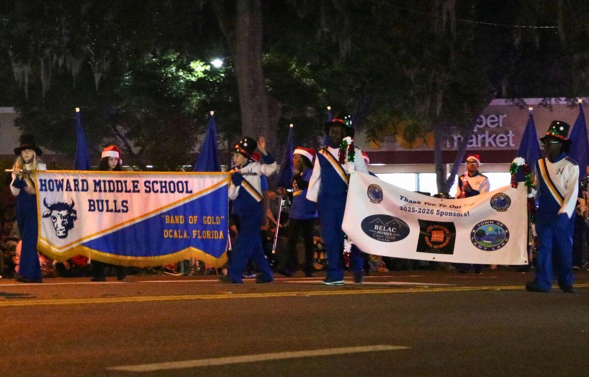 Students hold banners and flags at a parade. One of the banners read, "Howard Middle School Bulls."