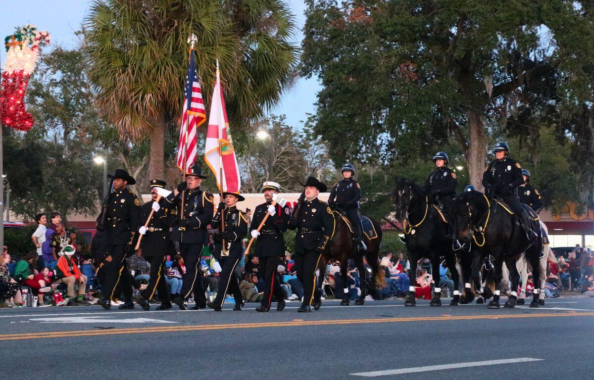Police walking and on horses holds flags and axes as they walk together.