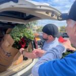 A man takes a pine wreath out of a box that's in an SUV.