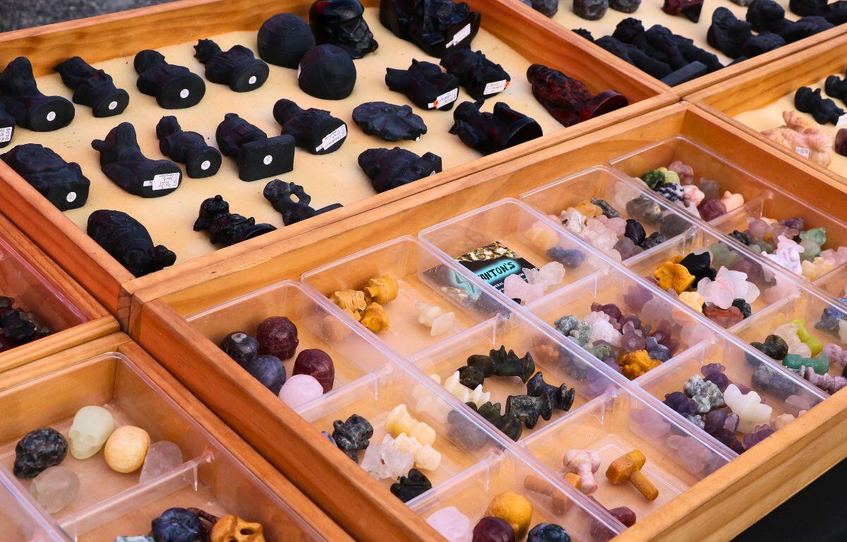 A wooden case displays small trinkets stored in clear boxes.