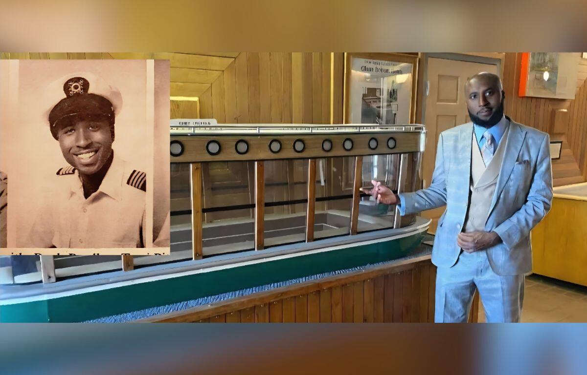 A portrait of a man in a uniform on the left, with a model of a glass-bottom boat, with a man in a blue suit standing to the right, with a white wall in the background, with an open door on the far right.