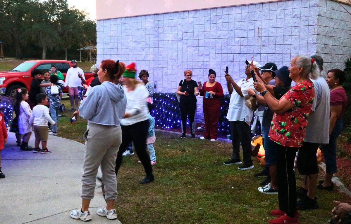 A crowd of people hold their phones up to record a Christmas tree lighting ceremony.