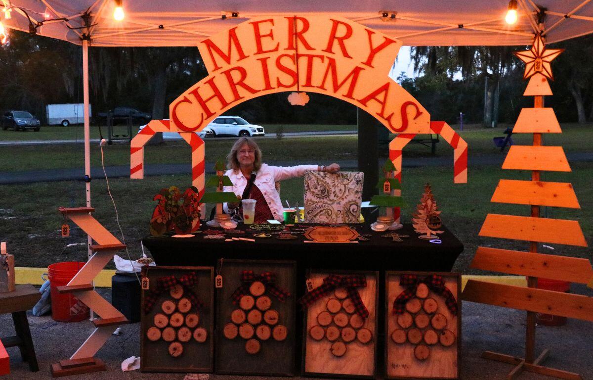 A vendor in a park features wood works displayed throughout the booth.