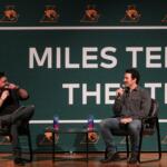 Miles Teller (right) and Ryan Downs (left) sit on black chairs in front of a sign that says "Miles Teller Theatre" for a Q&A session at a special assembly on Dec 5, 2025