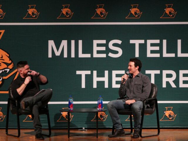 Miles Teller (right) and Ryan Downs (left) sit on black chairs in front of a sign that says "Miles Teller Theatre" for a Q&A session at a special assembly on Dec 5, 2025