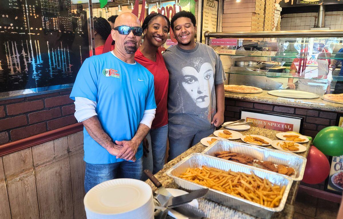 Employees in a pizzeria serve fires, chicken and pizza during a celebration event.