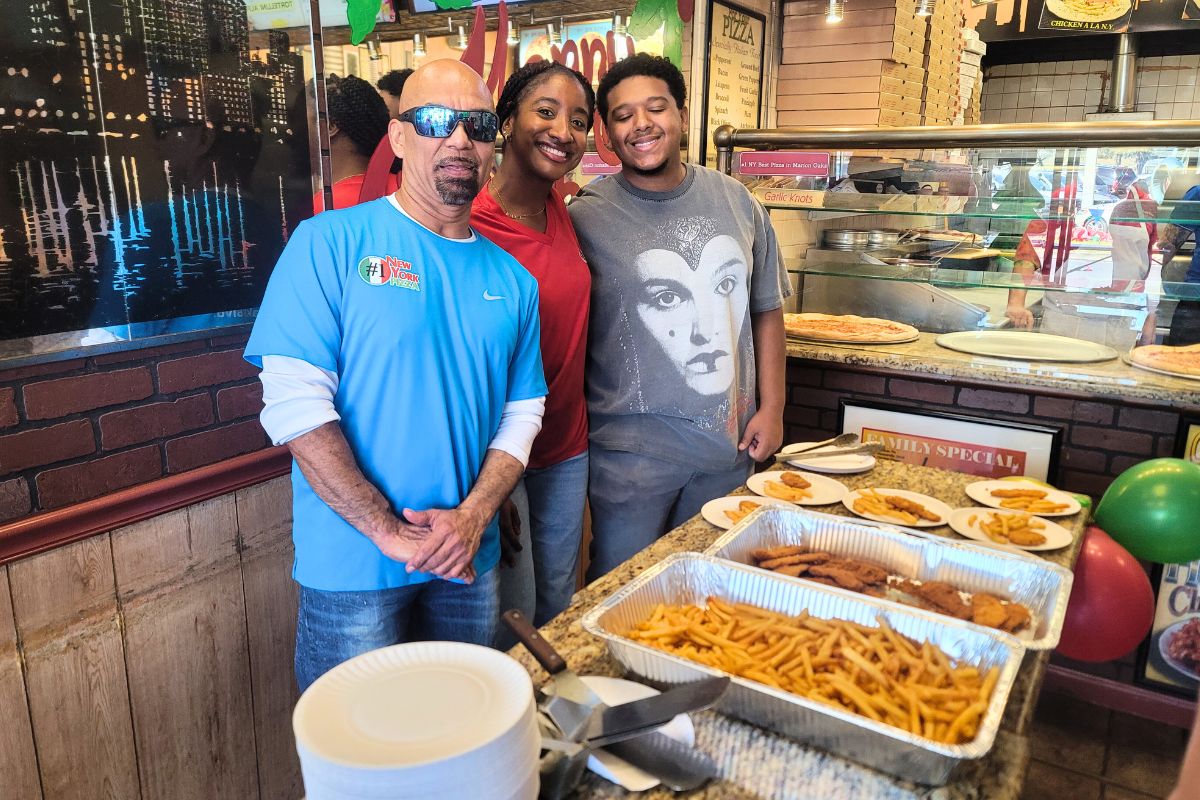 Employees in a pizzeria serve fires, chicken and pizza during a celebration event.