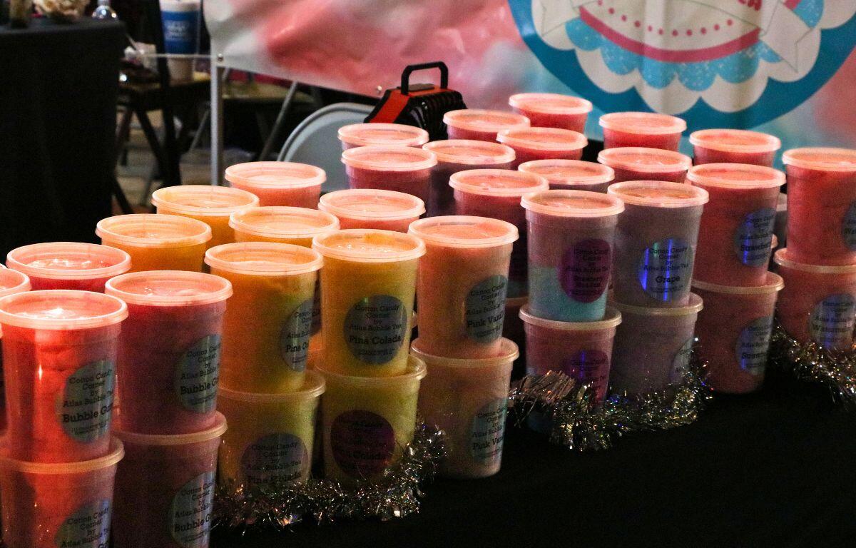 Plastic containers of cotton candy are stacked on top of each other on a table with a black tablecloth.