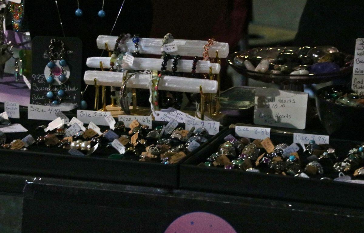 Jewelry is displayed in a black case, a bracelet rack and clear bowl.