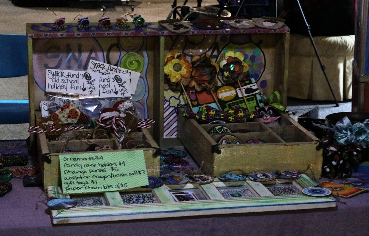 A box full of handcrafted items are displayed on a table with a purple tablecloth.