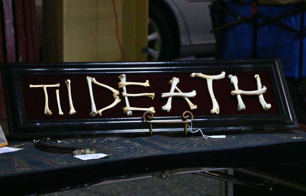 A black sign with a red, velvet interior has "Til Death" written in bone on top.