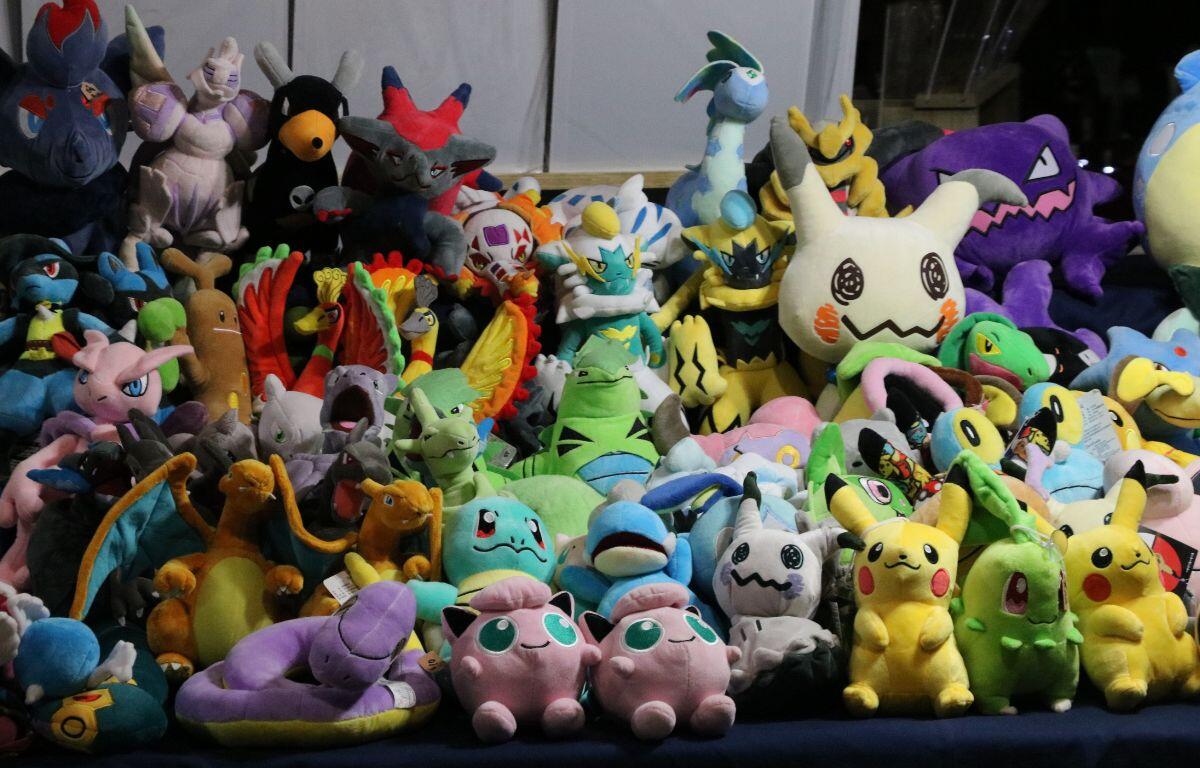 A variety of Pokémon plushies are lined together on a table for people to purchase.