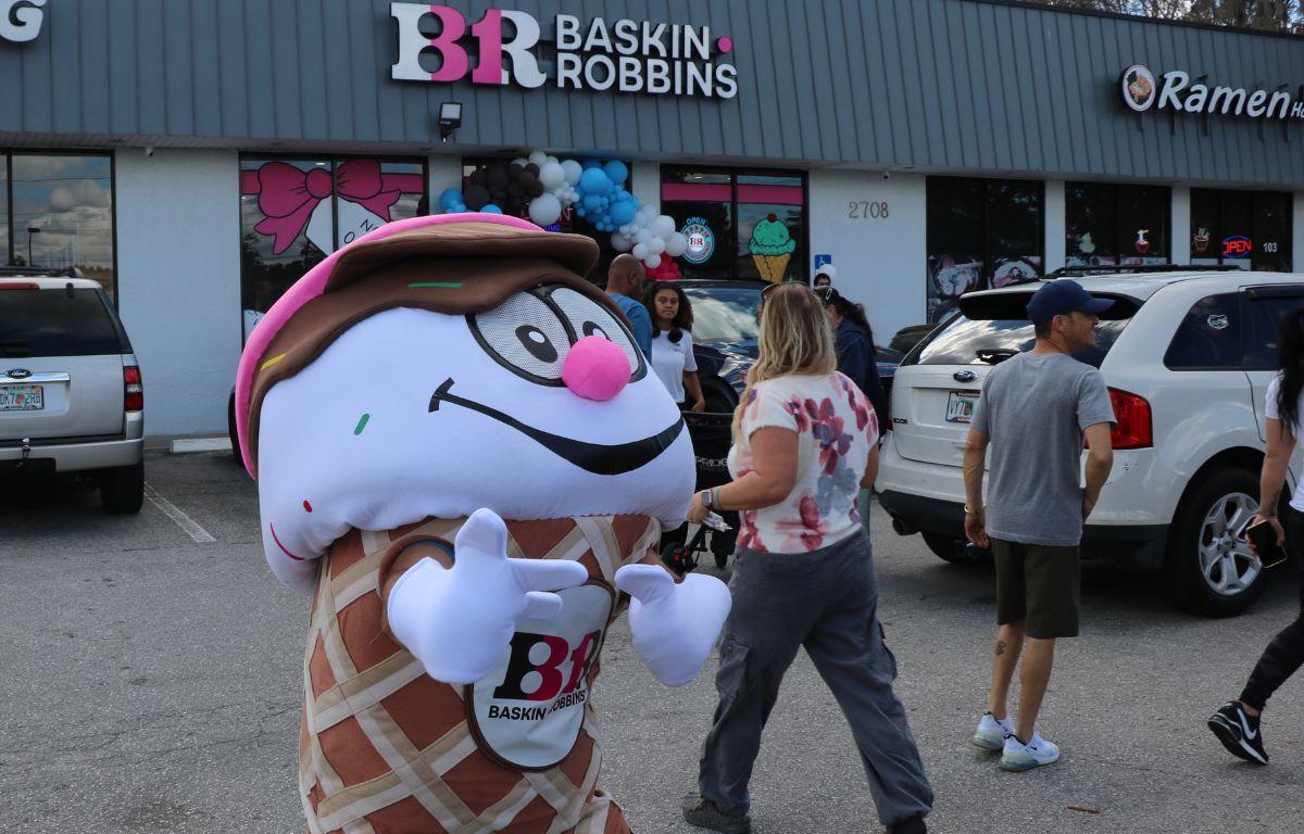 A person dressed as an ice cream cone in front of a Baskin Robbins, poses for a picture while advertising the new location.