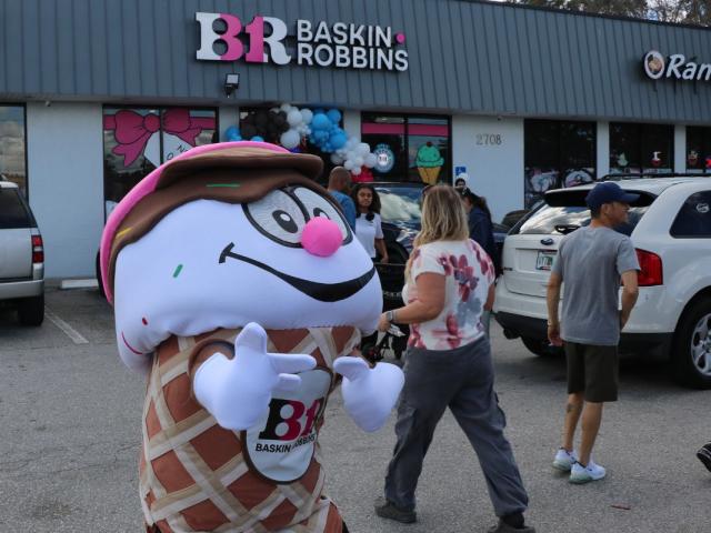 A person dressed as an ice cream cone in front of a Baskin Robbins, poses for a picture while advertising the new location.