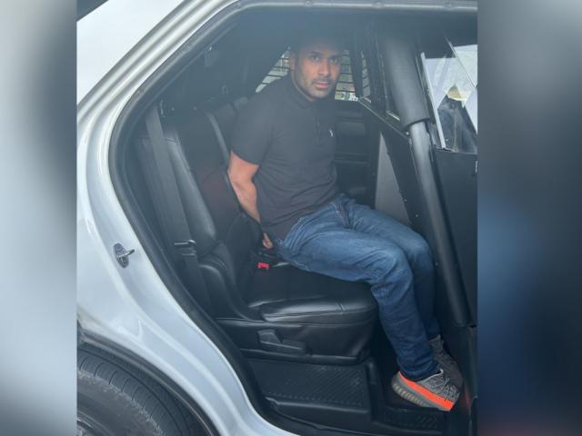 A man sitting in the back of a vehicle with his hands behind his back.