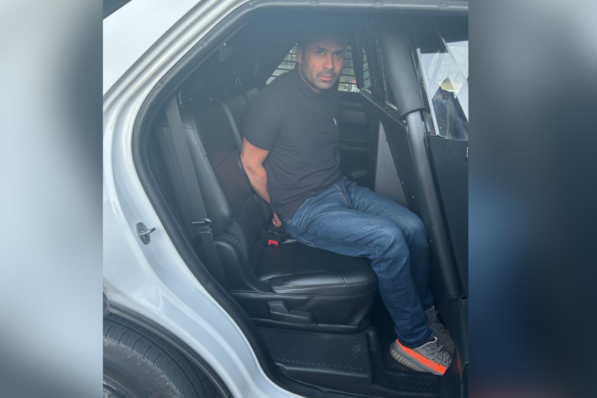 A man sitting in the back of a vehicle with his hands behind his back.