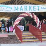 A large, open-air event area features a large balloon arch at the entrance with a white banner that reads, "Ocala Downtown Market. Sponsored by: Advent Health." A large market is taking place behind the entrance.