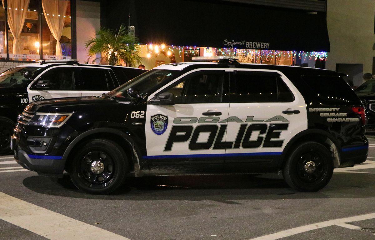 An Ocala police car sits in front of a line of shops at night. Lights hang from and overhang in front of Big Hammock's Brewery.