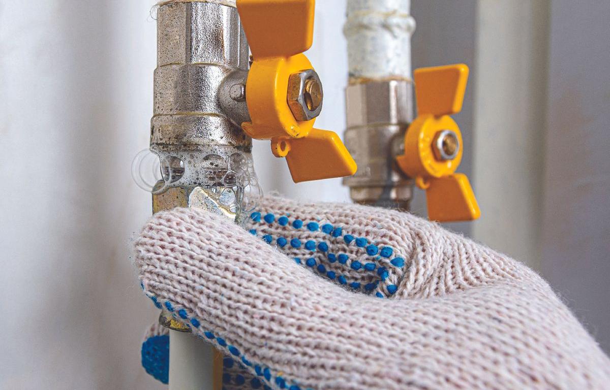 workers gloved hands working on natural gas line