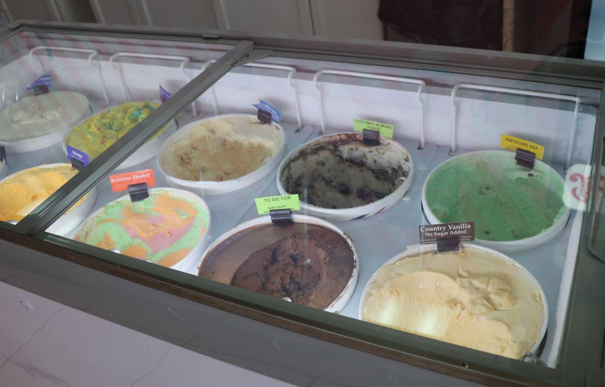Open tubs of ice cream with labels on top sit in lit coolers.