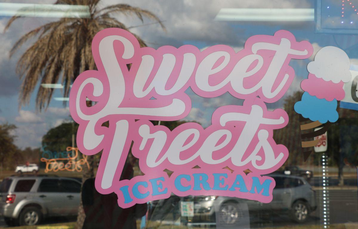A pink, white and blue sign on a glass window reads, "Sweet Treets Ice Cream."