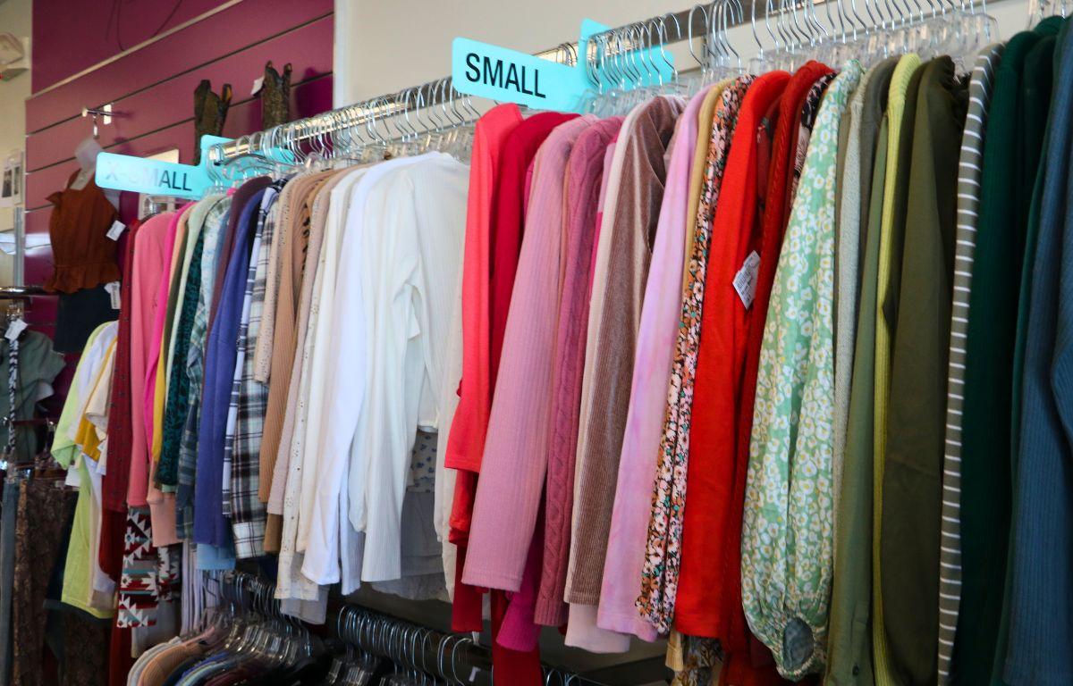 A rack of color-coordinated clothing from bright, red clothing to darker, green and blue clothing feature long, blue signs reading, "Small,' and, "X Small."